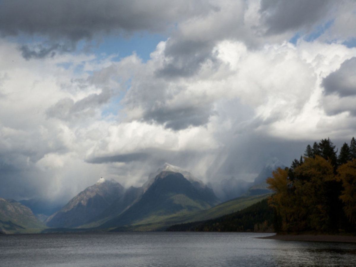 Original photograph of Lake McDonald: dark mountains below a cloudy sky, with a lake and wooded shoreline in the foreground.
